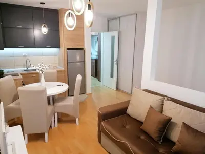 a living room and kitchen with a couch and a table at Emili Apartman in Jagodina