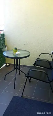 a glass table and two chairs in a room at Emili Apartman in Jagodina