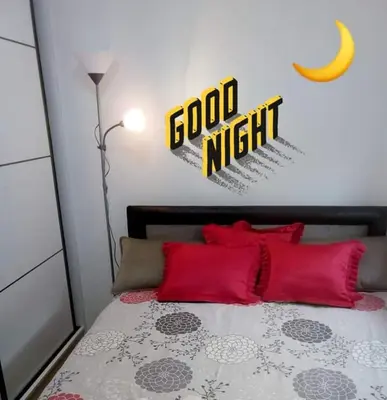 a bedroom with a bed with red pillows and acgi night sign at Apartman RADOVIĆ in Vrnjačka Banja