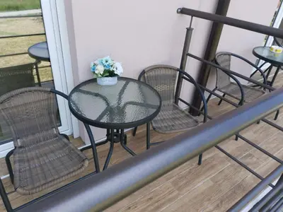 a table with chairs and a vase of flowers on a balcony at Apartman RADOVIĆ in Vrnjačka Banja