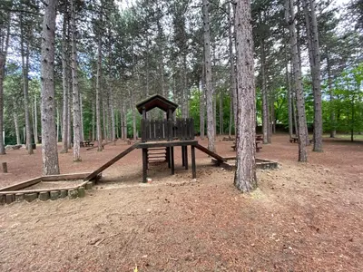 a playground in the middle of a forest with trees at Apartmani JOVANOVIC Sokobanja in Soko Banja