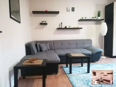 a living room with a blue couch and two tables at Viki Apartment CENTAR in Niš