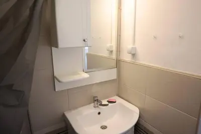 a white bathroom with a sink and a mirror at Viki Apartment CENTAR in Niš