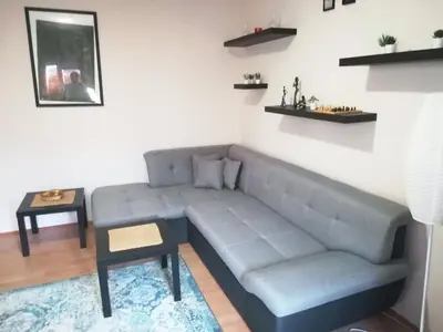 a living room with a blue couch and a table at Viki Apartment CENTAR in Niš