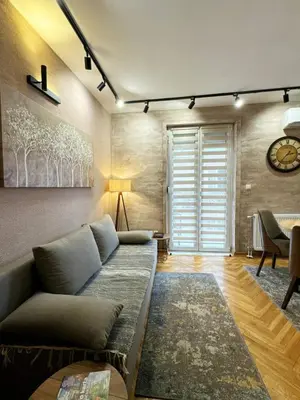 a living room with a couch and a clock on the wall at Apartman Lora in Vrnjci