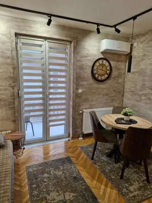 a living room with a table and a clock on the wall at Apartman Lora in Vrnjci