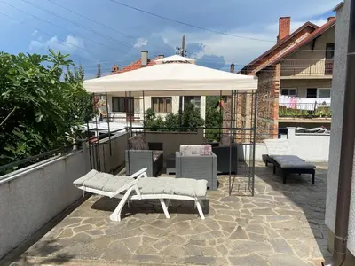a patio with two white chairs and an umbrella at Apartman Boskovic in Soko Banja