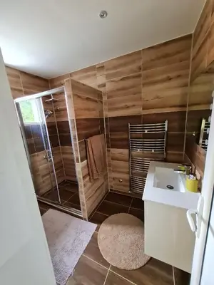 a bathroom with a sink and a shower with wooden walls at Apartman Boskovic in Soko Banja