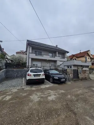 two cars parked in a parking lot in front of a house at Apartman Boskovic in Soko Banja