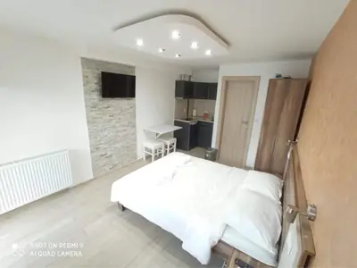 a bedroom with a white bed and a stone wall at Studio Dunja in Soko Banja