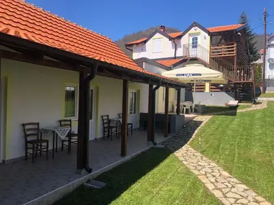 a patio with chairs and tables and a house at Vila Zdravković Prolom Banja in Prolomska Banja