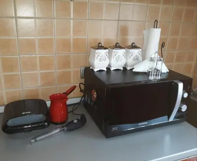 a microwave sitting on a kitchen counter with three mugs at Una in Vrnjačka Banja