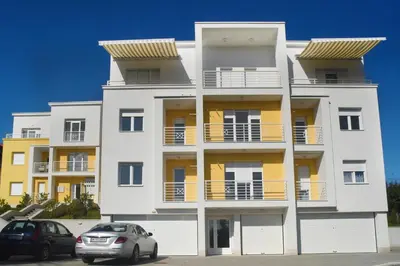 a white apartment building with two cars parked in front of it at Panoramske Vile in Vrnjačka Banja