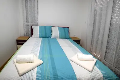 a large bed with blue and white sheets and pillows at Panoramske Vile in Vrnjačka Banja