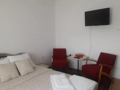 a bedroom with a bed and two chairs and a television at Kutak- stan na dan in Paraćin
