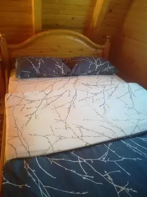 a bed with a blue comforter and pillows at Banjska brvnara in Vrnjačka Banja