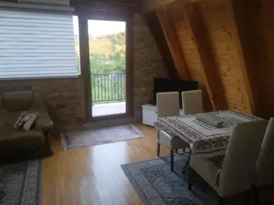 a living room with a table and chairs and a window at Banjska brvnara in Vrnjačka Banja