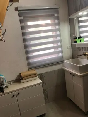 a bathroom with a sink and a window with blinds at Banjska brvnara in Vrnjačka Banja