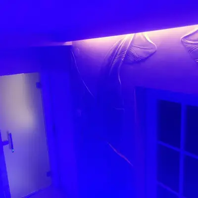 a bed in a room with a blue light at Apartman Cristallino in Niš