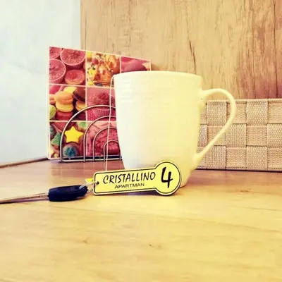 a sign sitting on the floor next to a cup at Apartman Cristallino in Niš