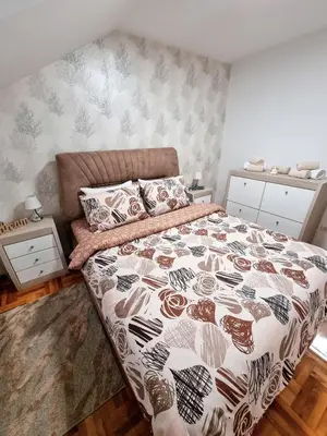 a bedroom with a bed with a brown and white comforter at AS Delux Apartmani in Soko Banja
