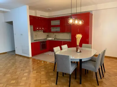 a kitchen with red cabinets and a table and chairs at Apartman Gogić in Vrnjačka Banja