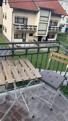 a wooden bench and a chair on a balcony at Apartman Gogić in Vrnjačka Banja