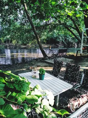 a picnic table and chairs next to a river at Milosev Konak in Aleksandrovac