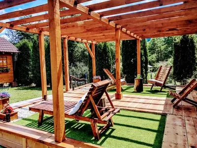 a wooden pergola with two chairs and a bench at Milosev Konak in Aleksandrovac