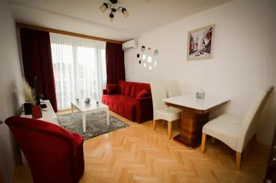 a living room with a red couch and a table at Apartman NINA in Vrnjačka Banja