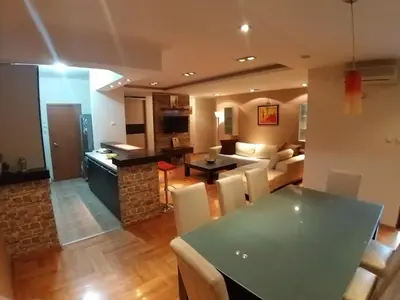 a kitchen and living room with a table and chairs at Brown Apartment - Niš Center in Niš