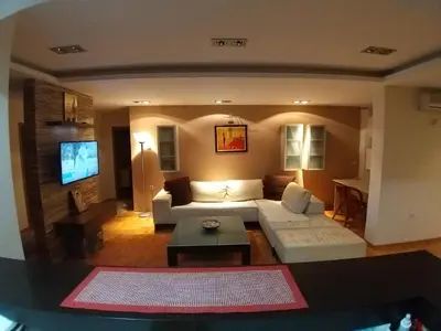 a living room with a white couch and a tv at Brown Apartment - Niš Center in Niš