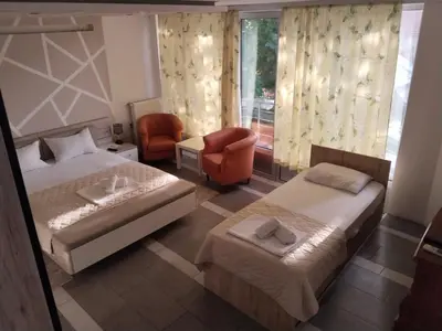 a bedroom with two beds and a chair and a window at LIRA EXCELLENT NIS in Niš