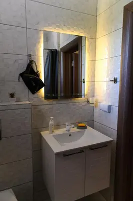 a white bathroom with a sink and a mirror at Apartman N&P in Soko Banja
