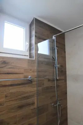 a bathroom with a shower with a wooden wall at Millenium apartment in Soko Banja