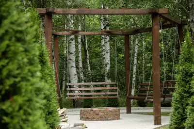 a wooden swing in a park with trees at Miletic Villas in Despotovac