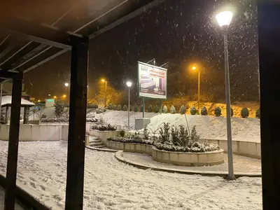 a park covered in snow with a sign and lights at 