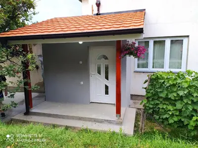 a small house with a white door and a porch at Apartman Ljiljan in Soko Banja