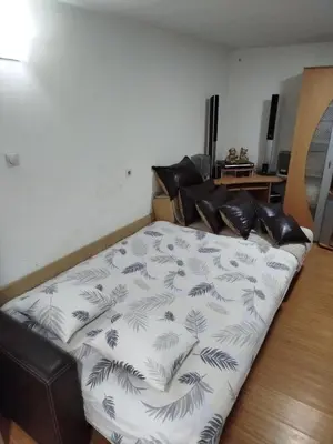 a bed with a black and white blanket on it at Apartmani Strahinic in Leskovac