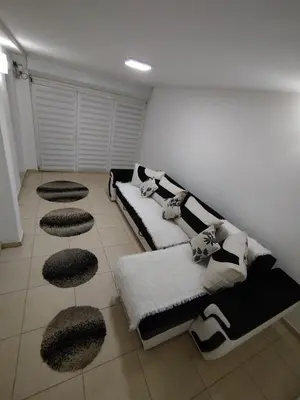 a living room with a couch and four circular stools at Apartmani Strahinic in Leskovac