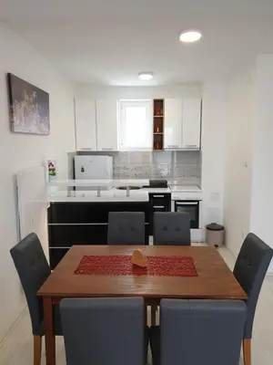 a dining room table with chairs and a kitchen at Sokolux in Soko Banja
