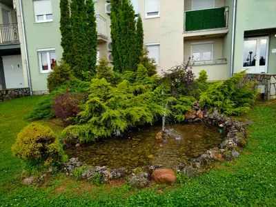 a garden in front of a building with a water fountain at Apartman Jovanovic in Vrnjačka Banja
