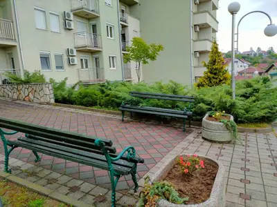 two park benches sitting on a brick patio in front of a building at Apartman Jovanovic in Vrnjačka Banja