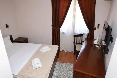 a bedroom with a bed and a desk and a window at DOWNTOWN ROOMS in Niš
