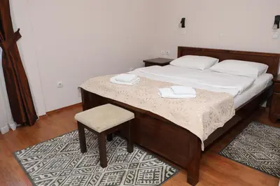 a bedroom with a bed with a chair and white sheets at DOWNTOWN ROOMS in Niš