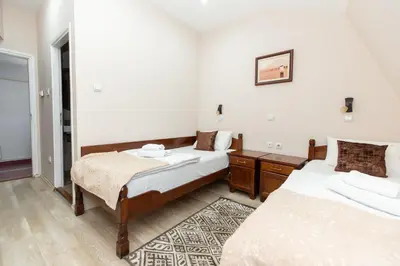 a bedroom with two beds and a rug at DOWNTOWN ROOMS in Niš