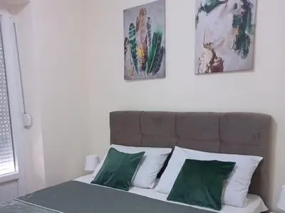 a bedroom with a bed with green and white pillows at Nina apartman in Vrnjačka Banja