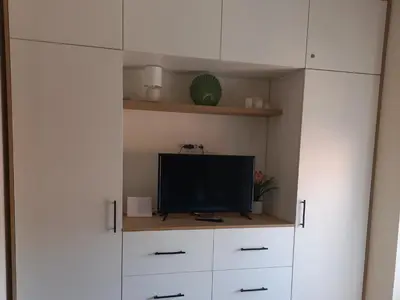 a living room with a tv and white cabinets at Nina apartman in Vrnjačka Banja