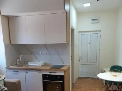 a kitchen with white cabinets and a table at Nina apartman in Vrnjačka Banja