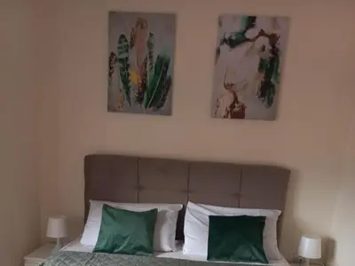 two paintings above a bed with green and white pillows at Nina apartman in Vrnjačka Banja